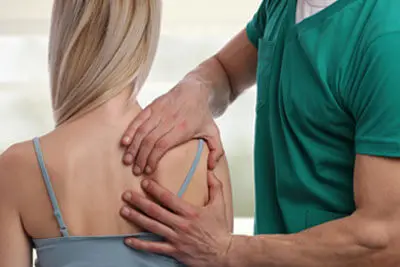 Person holding their lower back during assessment at Merivale Clinic in Ottawa